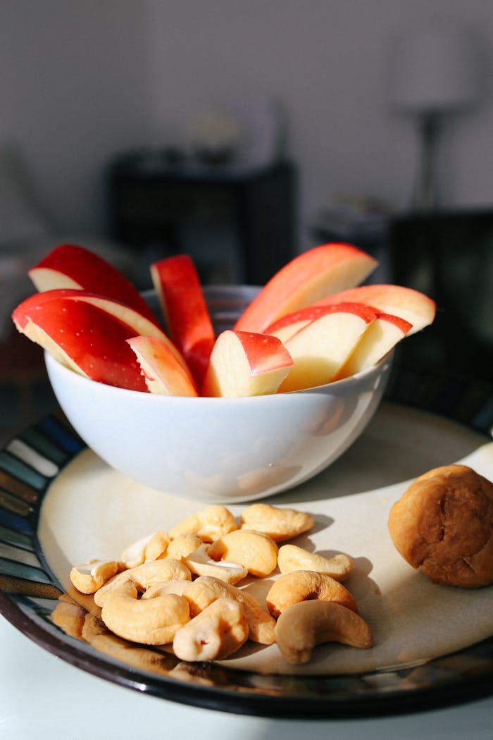 Home Bowl of sliced apples with cashews and fig on a plate. Perfect for healthy eating themes.